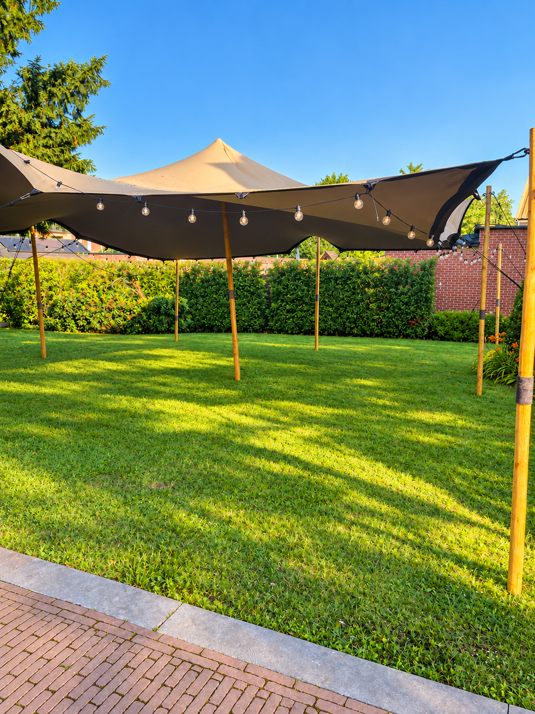 Beige stretchtent met lichtslingers in een zonnige tuin